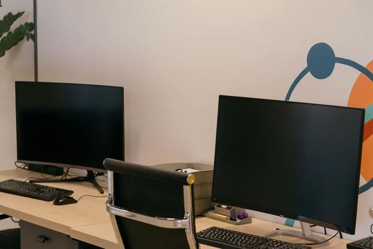 Two office monitors set up on a Singapore desk before a new joiner arrives