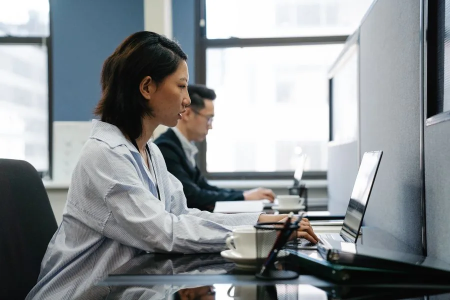 Colleagues working at desks beside a window in a modern Singapore office