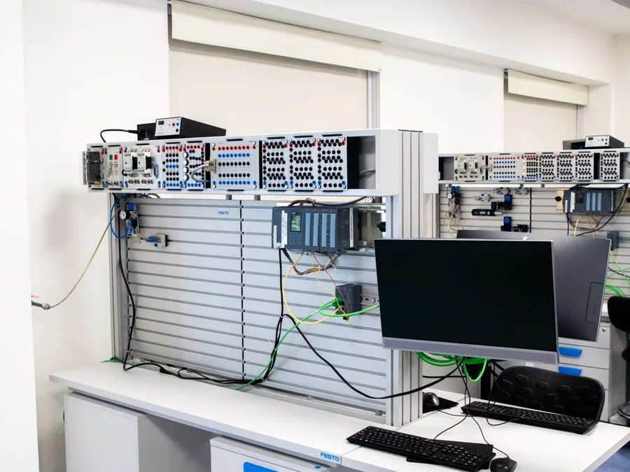 Wall-mounted comms panel with patched links and a staging monitor in a small equipment room