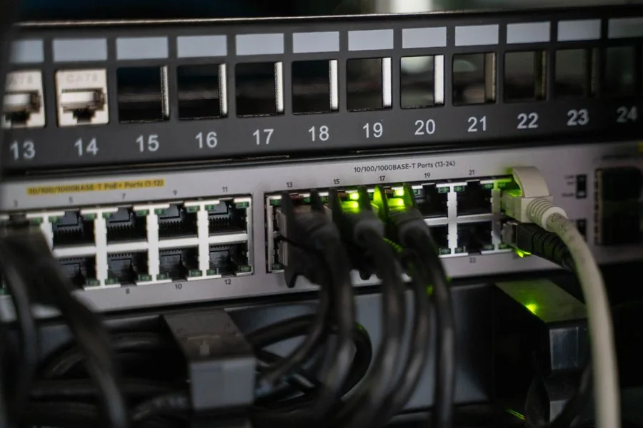 Rack-mounted managed switch with numbered ports and link lights in an office comms room