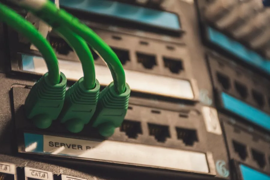 Green patch leads landing in a labelled comms-room panel above a rack
