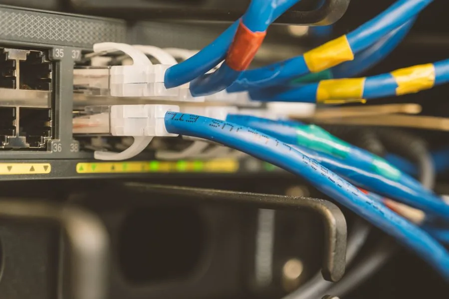 Blue and yellow patch leads landing in the front ports of a managed PoE switch