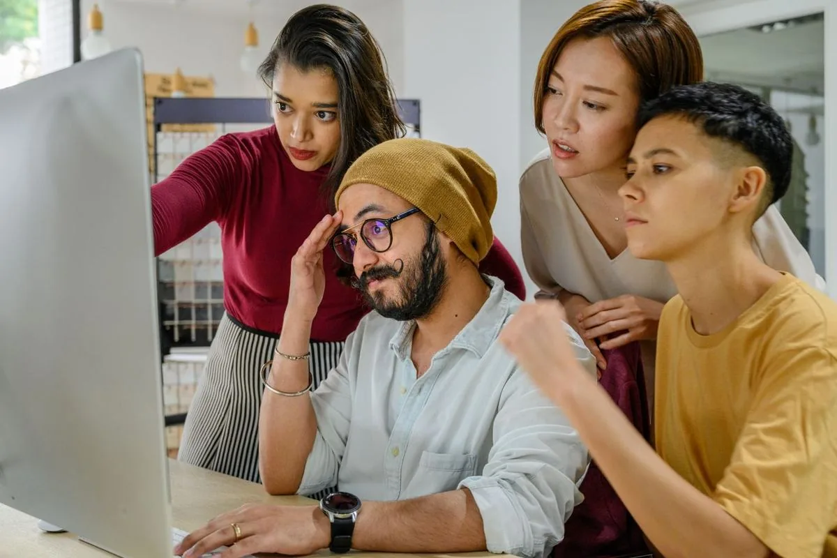 Four colleagues crowding round a monitor, looking for a mailbox that has disappeared